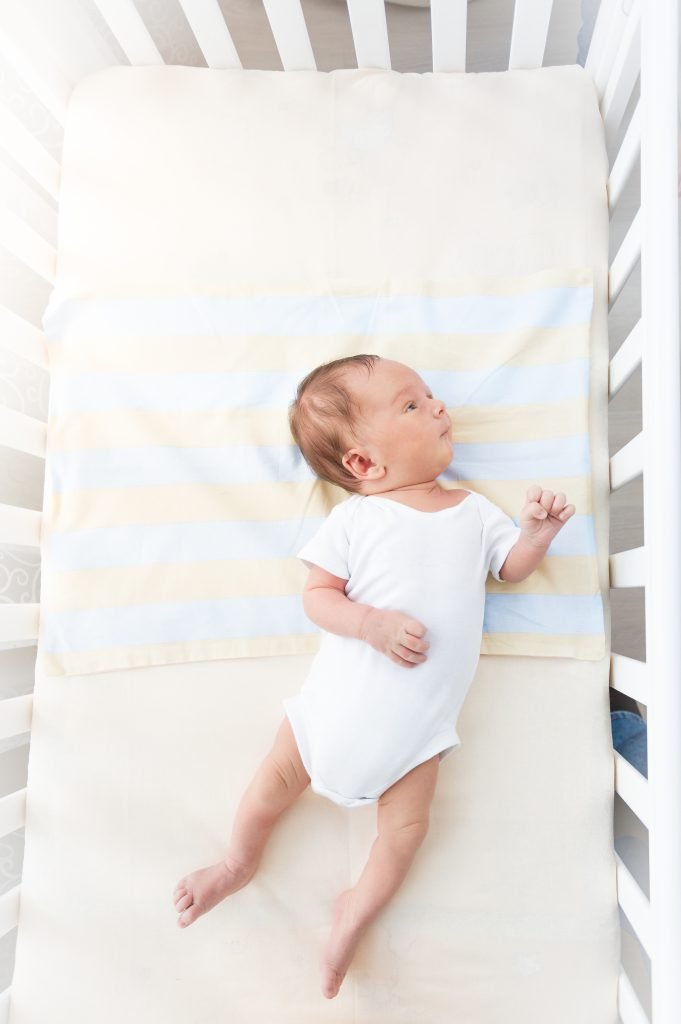 Baby laying in white crib.