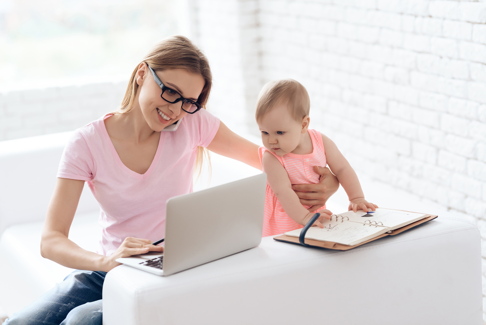 Young mother with baby working and using laptop. Motherhood concept.